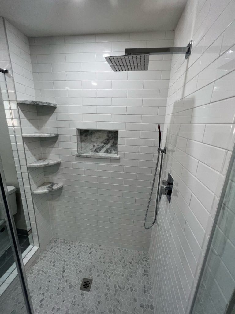 Walk-in shower with white subway tile and marble niche in a Spring Branch remodel