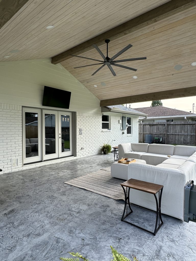 Covered patio with TV and outdoor seating at a Meyerland home, Houston
