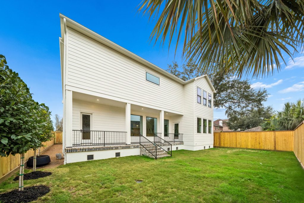 Back of a two-story Bellaire custom home with covered patio and lawn