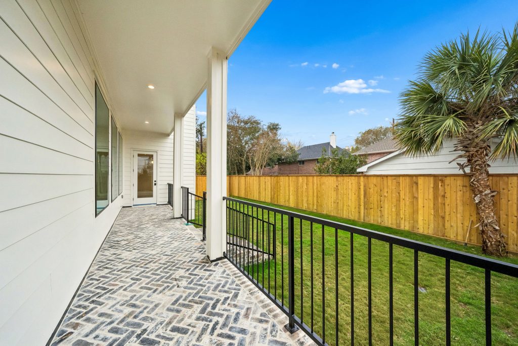 Covered back porch with herringbone brick pavers at a Bellaire new build