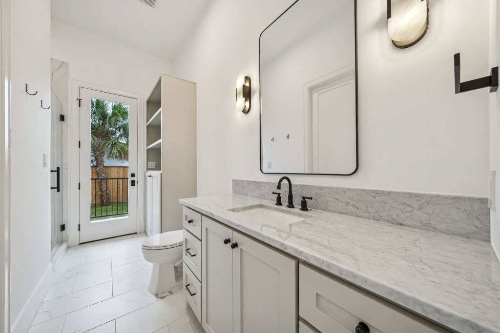 Bathroom with marble countertop vanity and black fixtures in a Bellaire custom home