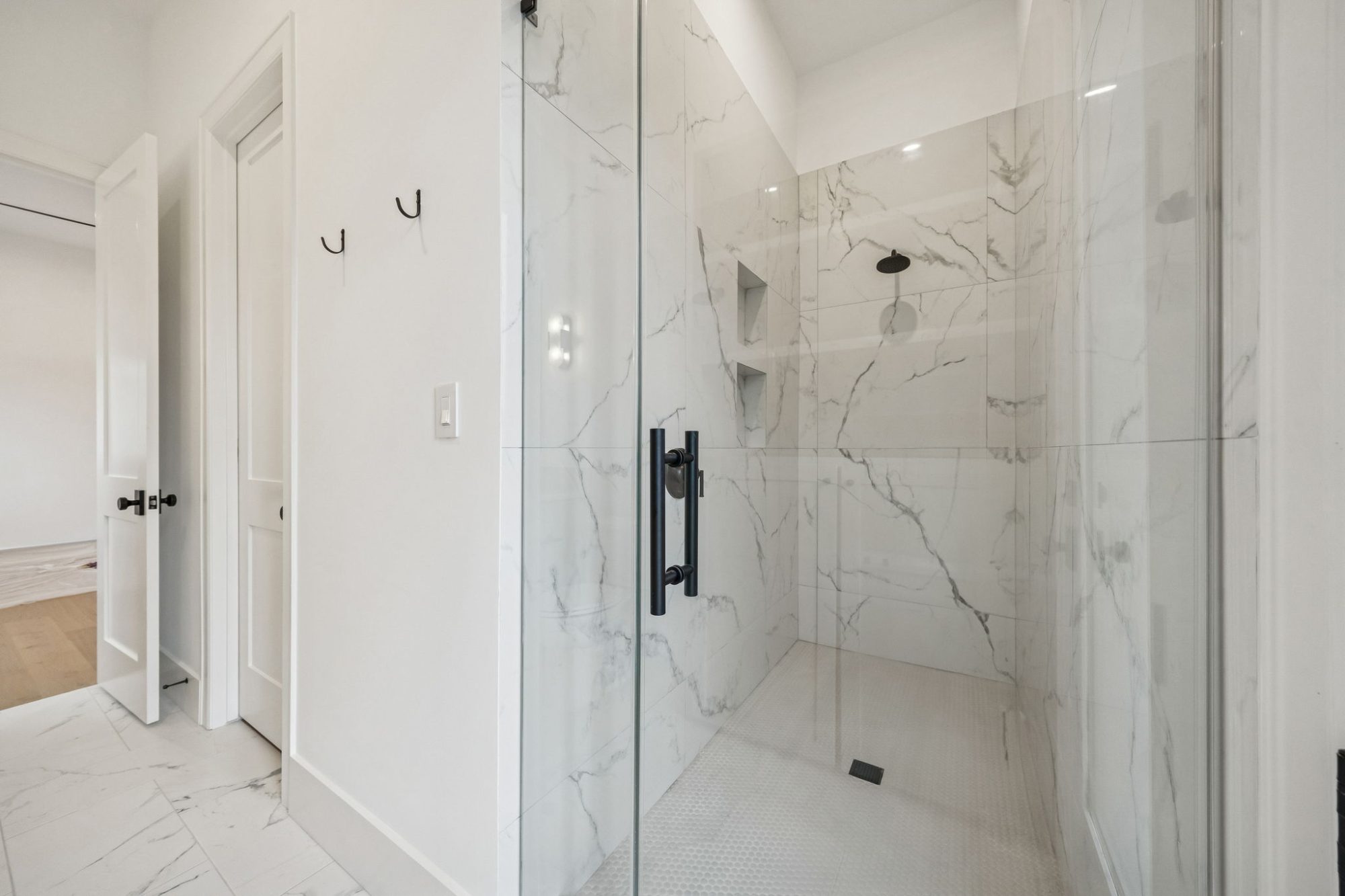 Glass walk-in shower with marble-look tile in a Bellaire new construction home