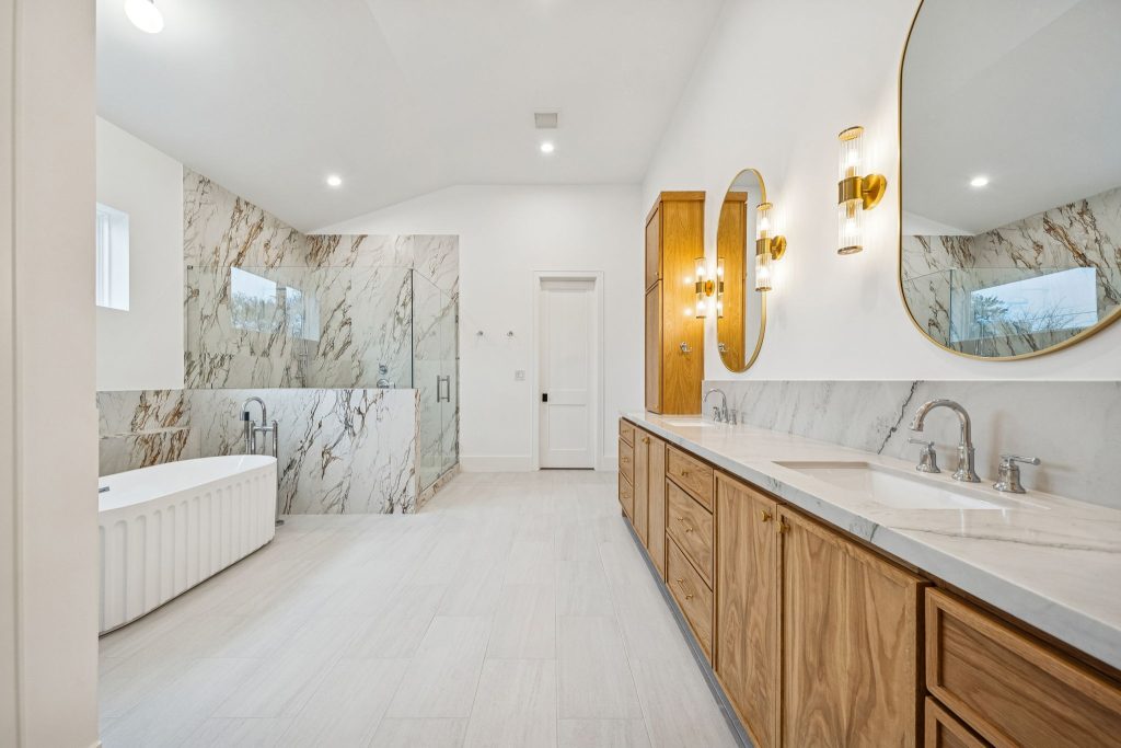 Primary bath with soaking tub, marble shower and wood double vanity in a Bellaire new build