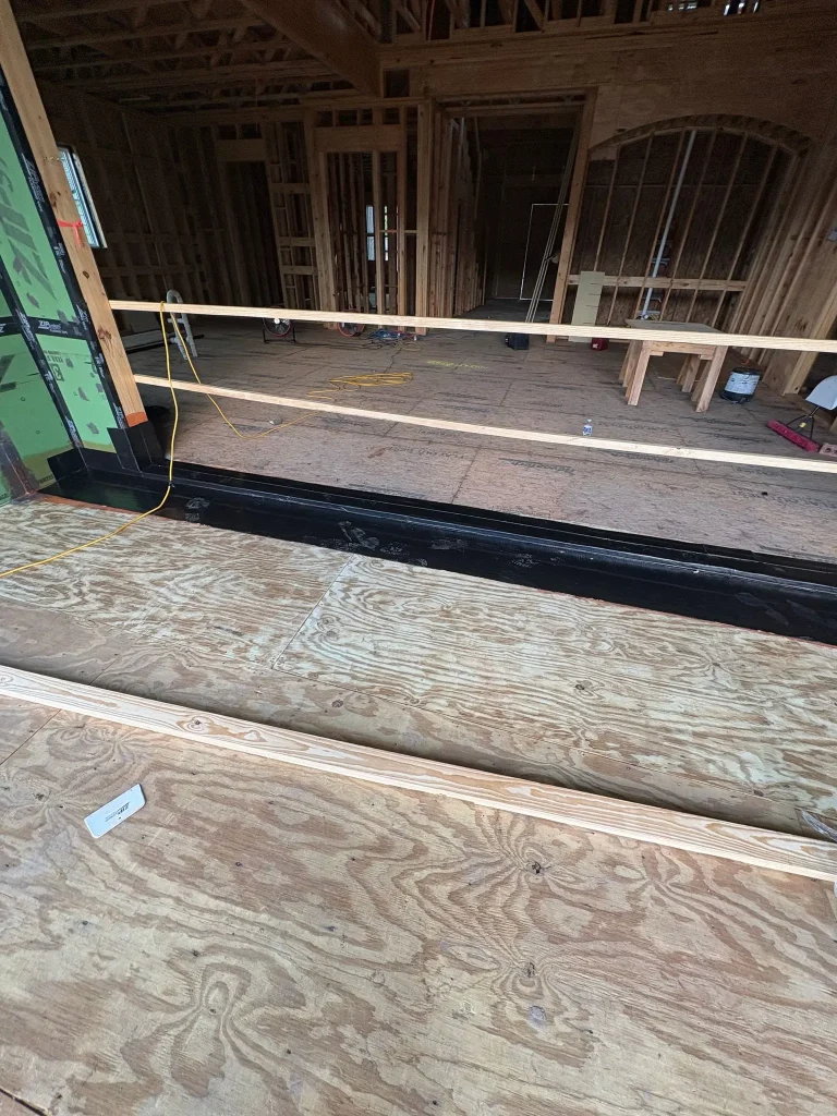 Waterproof membrane at the base of an exterior wall opening during construction
